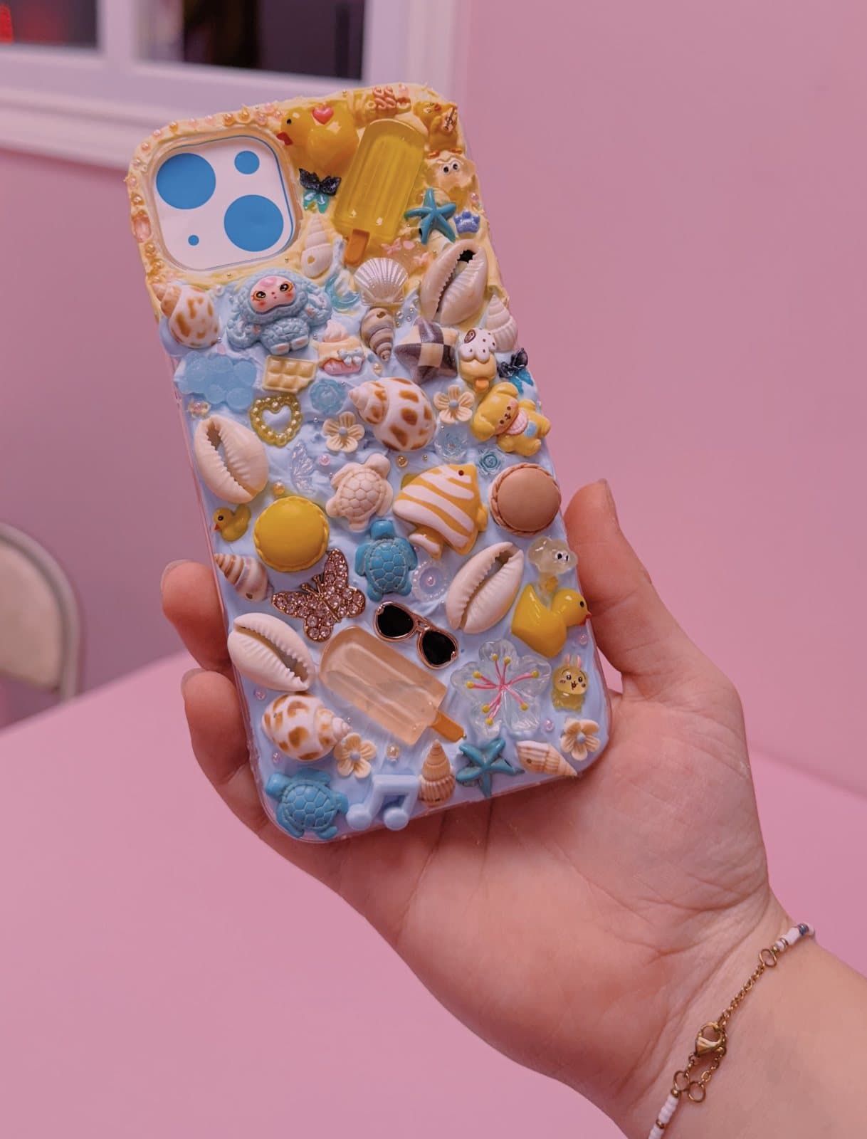 A finished ocean-themed decoden phone case held up in a hand