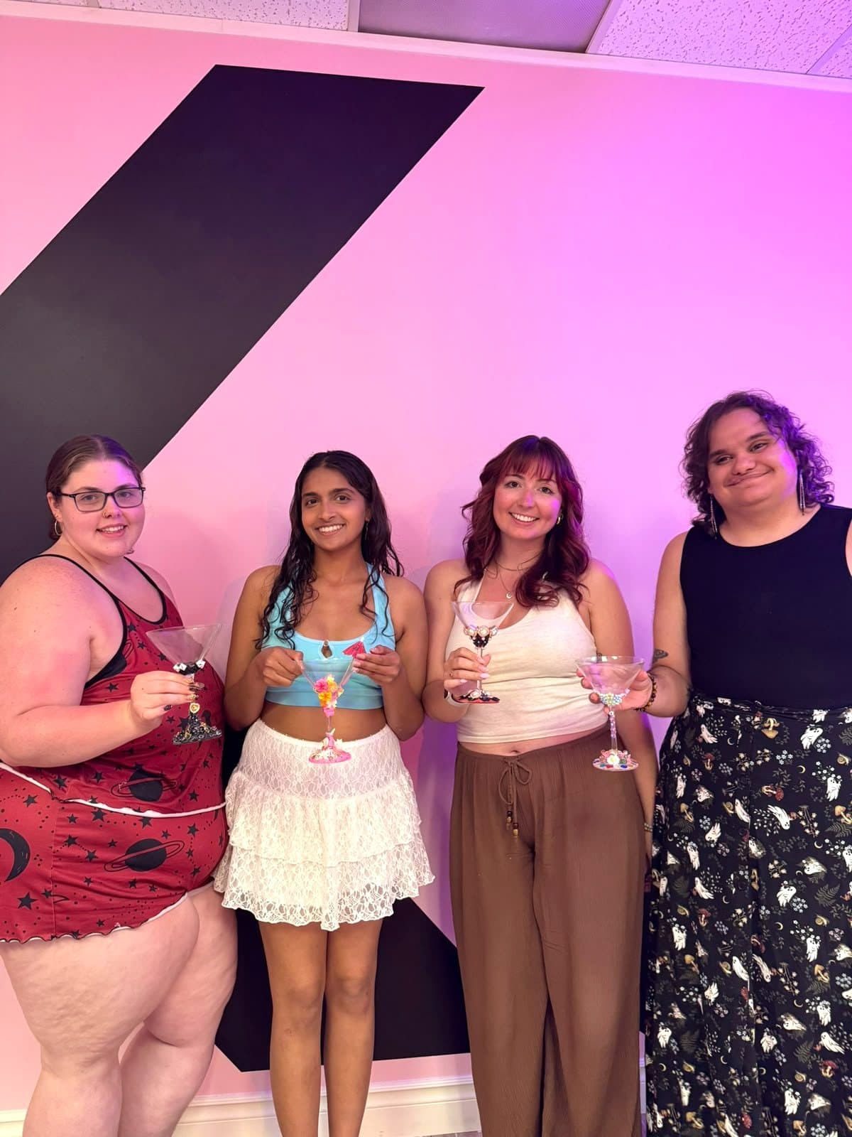 Four guests posing with the martini glasses they decorated